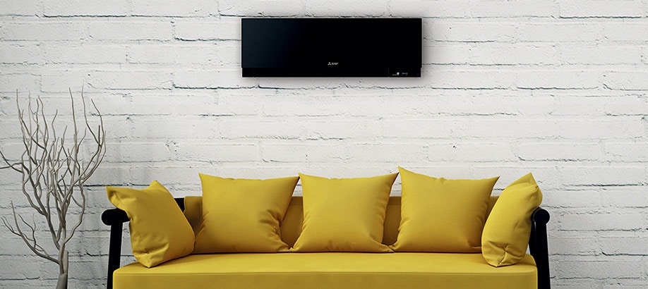 Condizionatore Mitsubishi MSZ-EF Kirigamine Zen nero a parete sopra un divano giallo