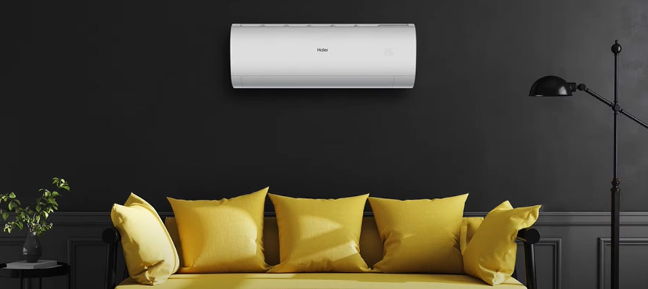 Condizionatore Haier Pearl su una parete grigia su un divano giallo in un salotto