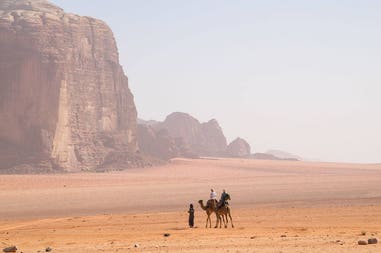 Cammelli e uomini nel deserto del Wadi Rum in Giordania